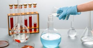 Jarak dekat seorang ilmuwan menuangkan cairan ke dalam flask di lingkungan laboratorium
