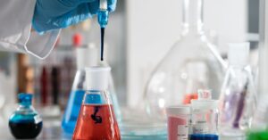 Ilmuwan yang melakukan percobaan laboratorium dengan larutan kimia berwarna-warni dan barang-barang kaca ilmiah.